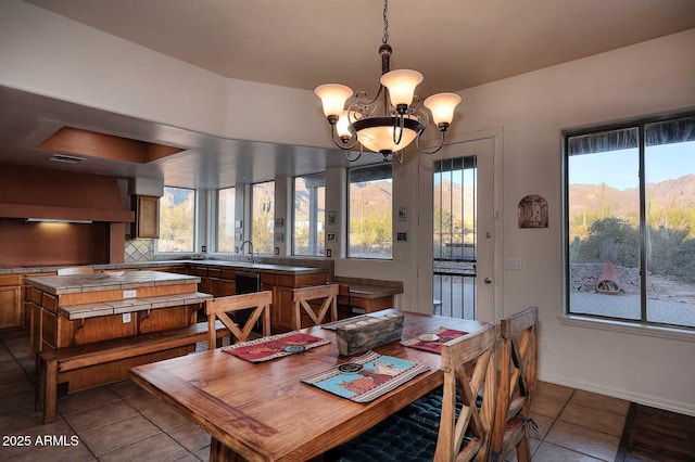 dining area with light tile patterned flooring, a mountain view, and a notable chandelier