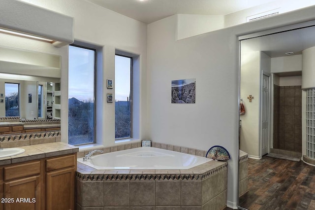 bathroom featuring a garden tub, a wealth of natural light, visible vents, vanity, and wood finished floors