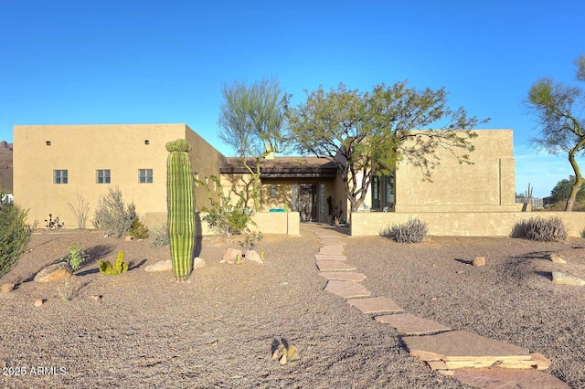 rear view of house featuring stucco siding