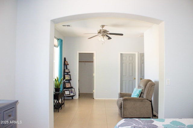 15148 W Sells Dr, Goodyear, AZ 85395 - bedroom with arched walkways, light tile patterned floors, a walk in closet, and a ceiling fan
