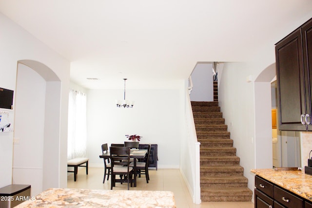 15148 W Sells Dr, Goodyear, AZ 85395 - dining room with arched walkways, stairs, light tile patterned floors, and baseboards