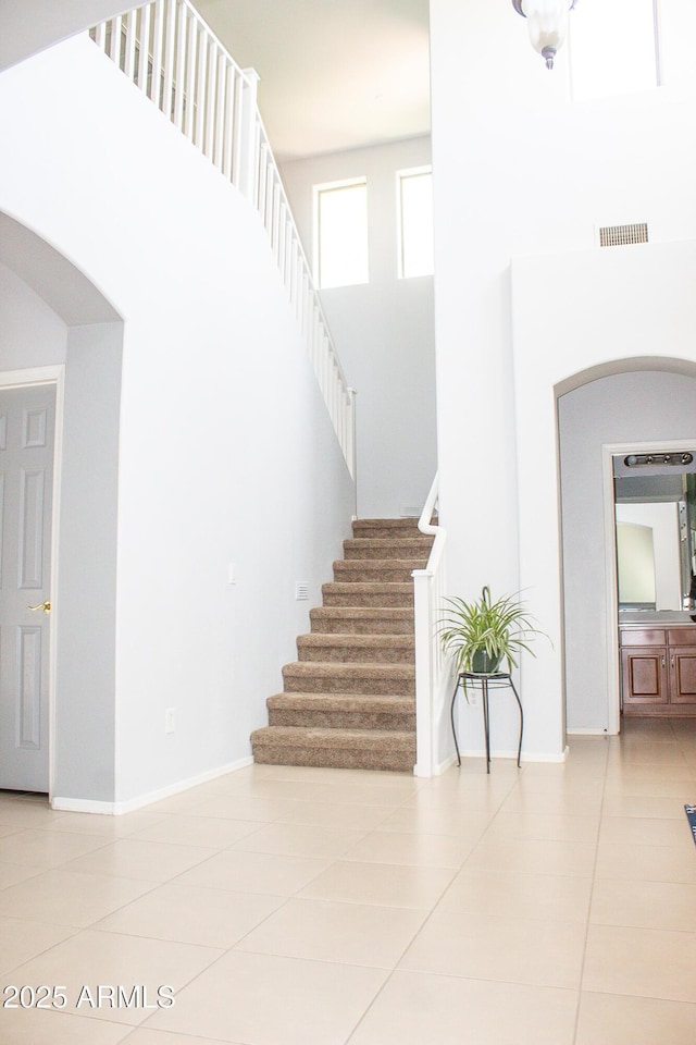 15148 W Sells Dr, Goodyear, AZ 85395 - stairs featuring tile patterned flooring, arched walkways, a high ceiling, and baseboards