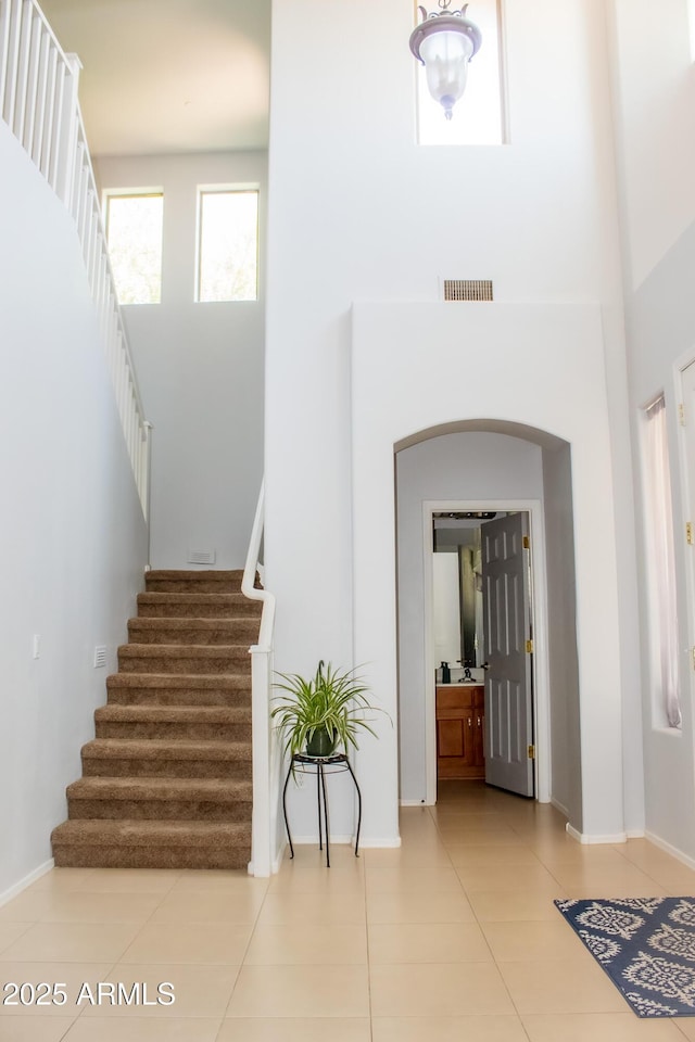 15148 W Sells Dr, Goodyear, AZ 85395 - tiled entryway featuring stairway, a towering ceiling, baseboards, and arched walkways