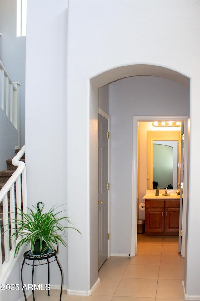 15148 W Sells Dr, Goodyear, AZ 85395 - hallway with arched walkways, light tile patterned flooring, stairs, and baseboards