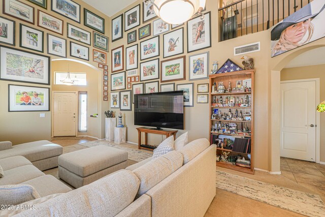 44890 W Desert Garden Rd, Maricopa, AZ 85139 - living room with arched walkways, a towering ceiling, carpet flooring, a chandelier, and baseboards