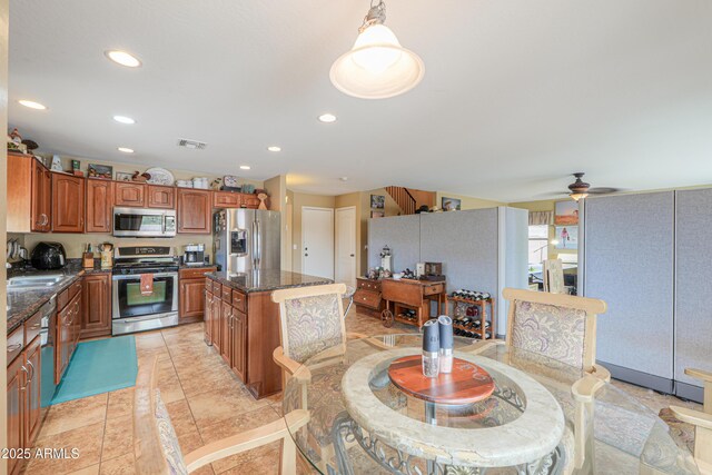 44890 W Desert Garden Rd, Maricopa, AZ 85139 - kitchen with stainless steel appliances, a kitchen island, brown cabinetry, recessed lighting, and dark stone countertops