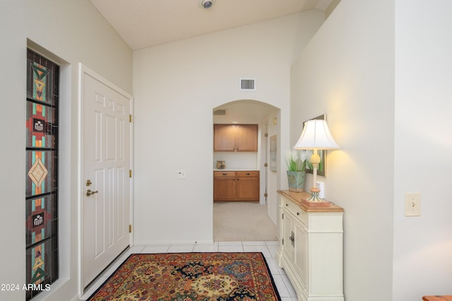 hallway with light tile patterned flooring and high vaulted ceiling