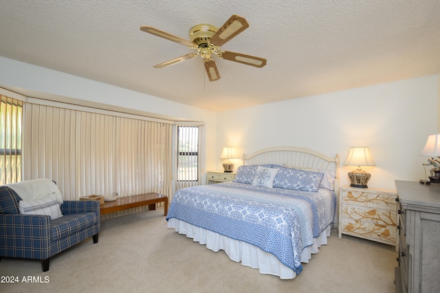 bedroom with a textured ceiling, light colored carpet, and ceiling fan