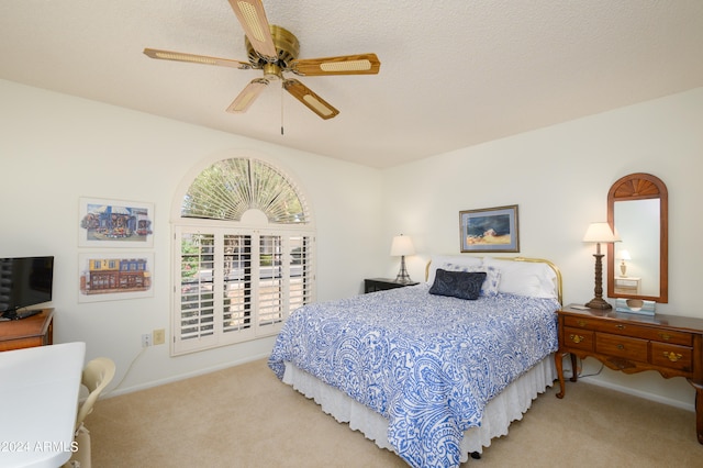 bedroom featuring a textured ceiling, light colored carpet, and ceiling fan