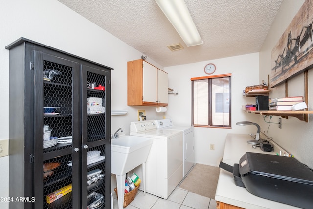 clothes washing area featuring light tile patterned floors, a textured ceiling, cabinets, and separate washer and dryer