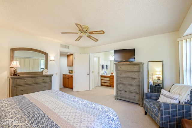 carpeted bedroom featuring a textured ceiling, ensuite bathroom, and ceiling fan