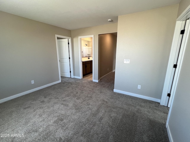 unfurnished bedroom with a sink, baseboards, carpet floors, and connected bathroom