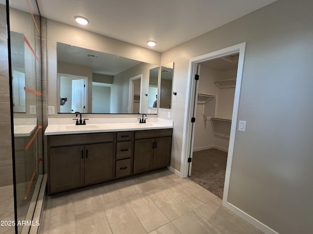 bathroom with a spacious closet, double vanity, baseboards, and a sink