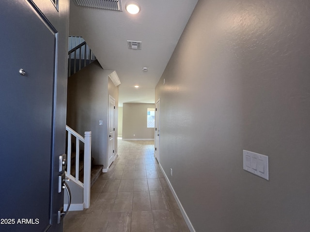 corridor featuring stairs, baseboards, and visible vents