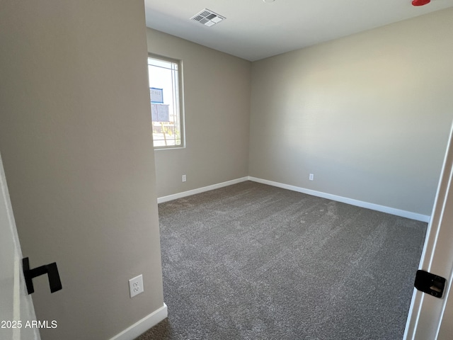 empty room with visible vents, baseboards, and dark carpet