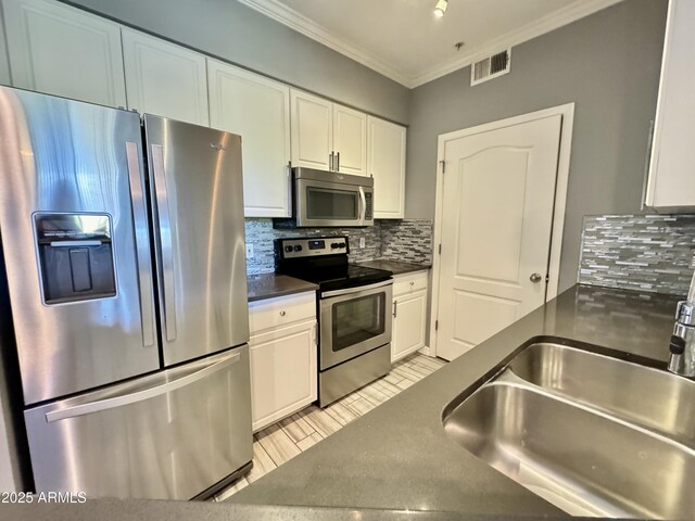 kitchen with visible vents, dark countertops, appliances with stainless steel finishes, white cabinetry, and a sink