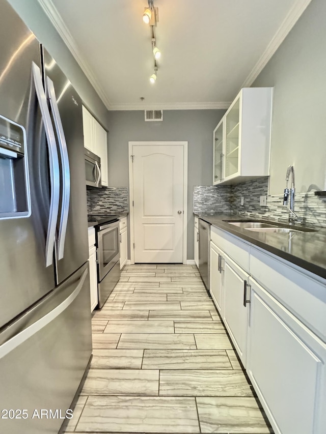 kitchen featuring a sink, white cabinets, appliances with stainless steel finishes, dark countertops, and glass insert cabinets