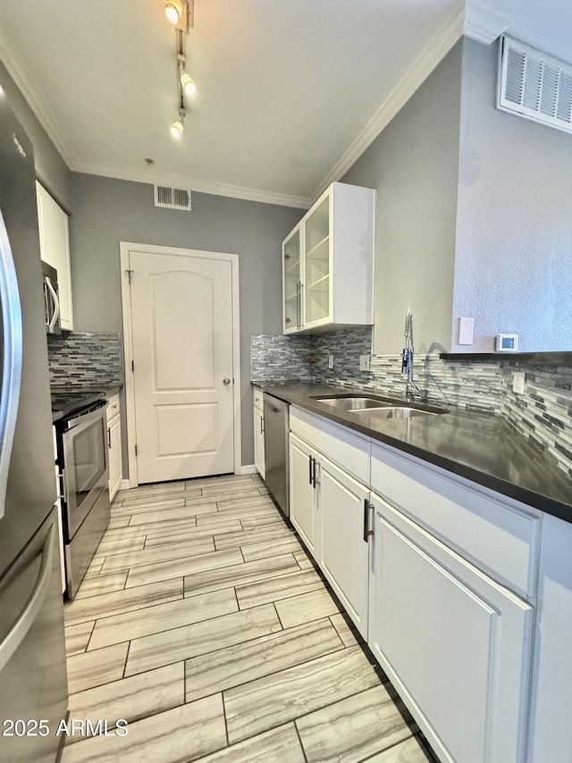 kitchen featuring glass insert cabinets, dark countertops, white cabinets, and appliances with stainless steel finishes