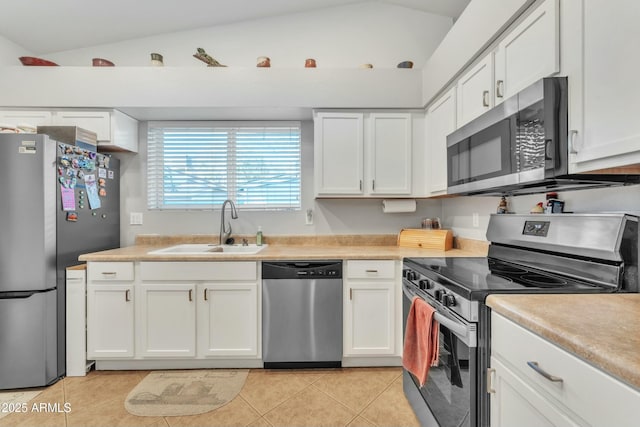 kitchen with lofted ceiling, appliances with stainless steel finishes, sink, and white cabinets