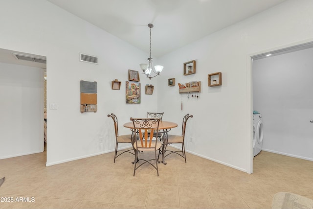 dining room featuring washer / dryer, light tile patterned floors, and an inviting chandelier