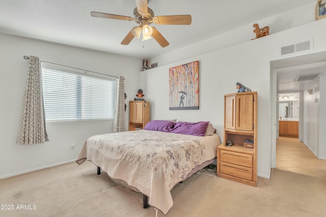 bedroom featuring light carpet, ensuite bath, and ceiling fan