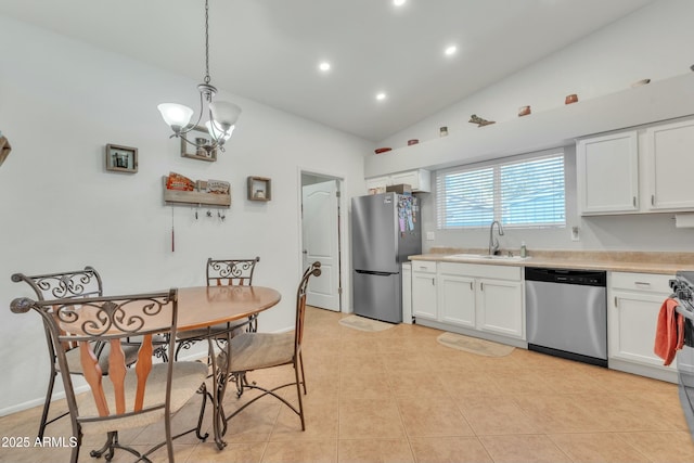 kitchen featuring pendant lighting, lofted ceiling, sink, white cabinets, and stainless steel appliances