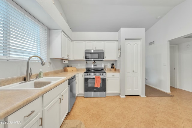 kitchen with white cabinetry, stainless steel appliances, light tile patterned flooring, and sink