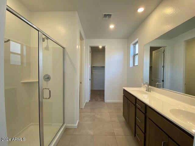 bathroom featuring a shower with door, vanity, and tile patterned flooring