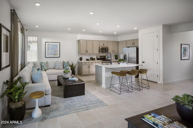 kitchen featuring a breakfast bar, a kitchen island with sink, stainless steel appliances, and light tile patterned floors