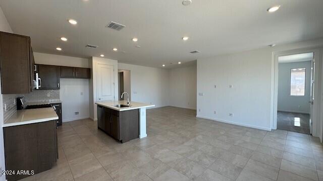 kitchen featuring a kitchen island with sink, sink, and tasteful backsplash