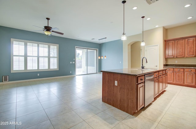 kitchen featuring sink, dark stone countertops, an island with sink, decorative light fixtures, and stainless steel dishwasher