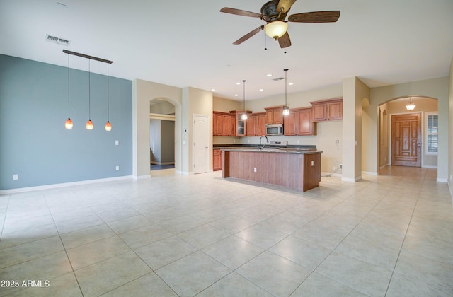 kitchen with pendant lighting, light tile patterned floors, sink, ceiling fan, and an island with sink