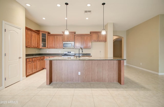 kitchen featuring appliances with stainless steel finishes, sink, a center island with sink, and dark stone counters