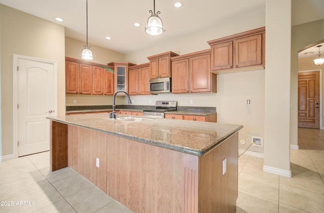 kitchen featuring dark stone countertops, sink, a kitchen island with sink, and stainless steel appliances