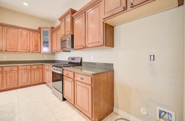 kitchen with dark stone countertops, stainless steel appliances, and light tile patterned floors