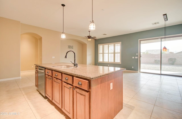 kitchen featuring sink, light stone countertops, an island with sink, decorative light fixtures, and stainless steel dishwasher