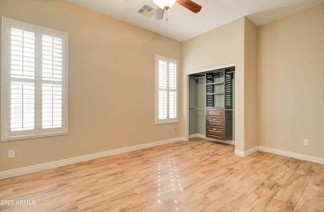 empty room featuring ceiling fan, a wealth of natural light, and light wood-type flooring