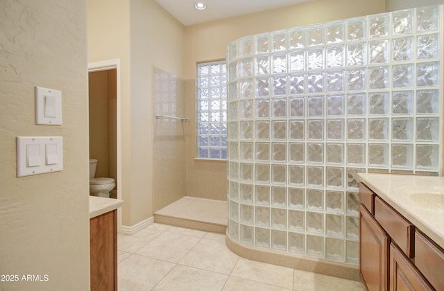 bathroom featuring vanity, tiled shower, tile patterned floors, and toilet