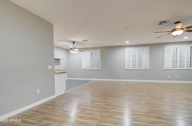 unfurnished living room featuring a wealth of natural light, ceiling fan, and light hardwood / wood-style flooring