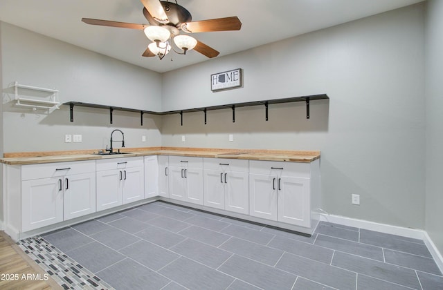 kitchen with white cabinetry, sink, ceiling fan, and wood counters