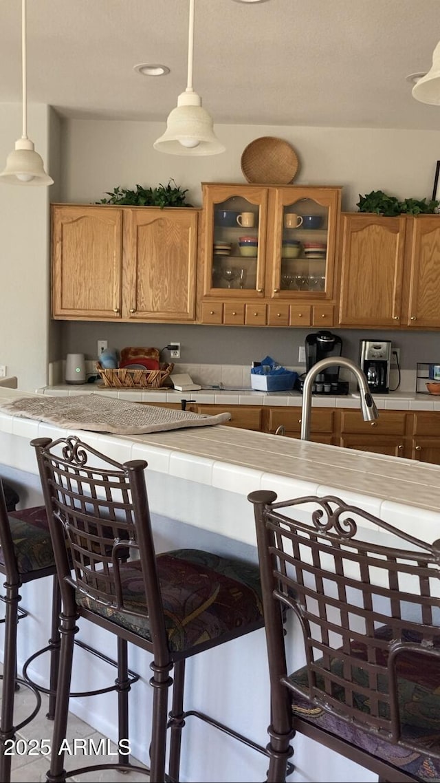 15753 W Kino Dr, Surprise, AZ 85374 - kitchen with tile counters, a breakfast bar area, and pendant lighting