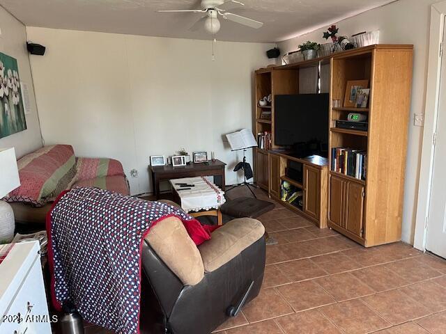 living area with ceiling fan and tile patterned floors