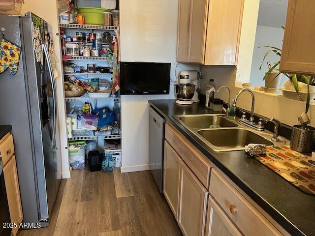 kitchen featuring dark countertops, dark wood-style floors, appliances with stainless steel finishes, and a sink