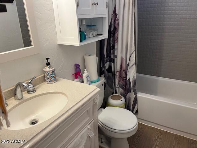 full bath featuring vanity, wood finished floors, toilet, and shower / bathtub combination with curtain