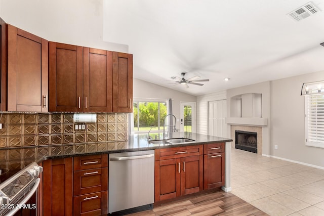 723 N Joshua Tree Ln, Gilbert, AZ 85234 - kitchen featuring stainless steel appliances, tasteful backsplash, ceiling fan, a tile fireplace, and lofted ceiling