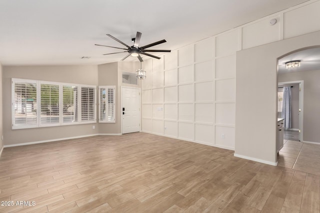 723 N Joshua Tree Ln, Gilbert, AZ 85234 - unfurnished living room featuring a ceiling fan, lofted ceiling, light wood-type flooring, and arched walkways
