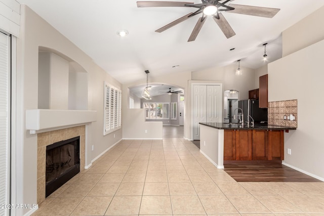 723 N Joshua Tree Ln, Gilbert, AZ 85234 - kitchen featuring ceiling fan, freestanding refrigerator, a tiled fireplace, a peninsula, and light tile patterned flooring