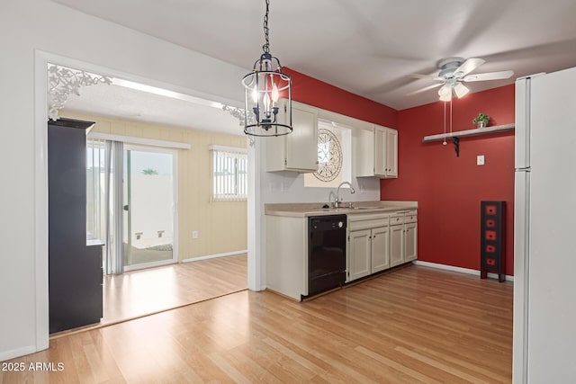 kitchen featuring light wood finished floors, dishwasher, freestanding refrigerator, and a sink