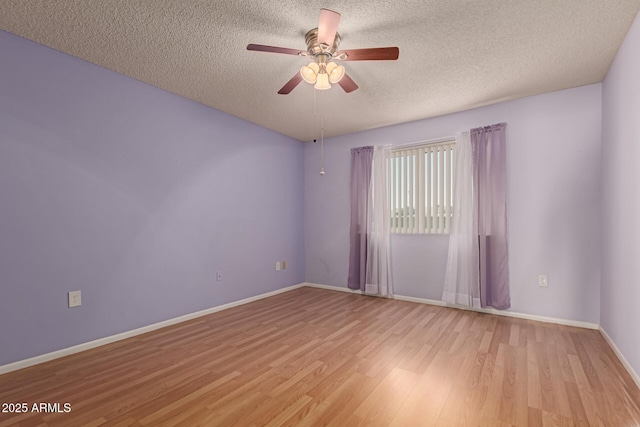 spare room with baseboards, ceiling fan, a textured ceiling, and light wood-style floors