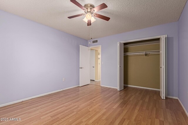 unfurnished bedroom with baseboards, a textured ceiling, and light wood-style floors